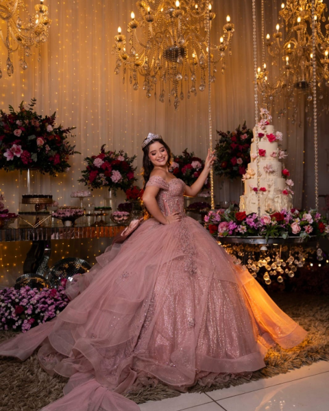 Debutante em vestido rosa com decoração de flores e lustres