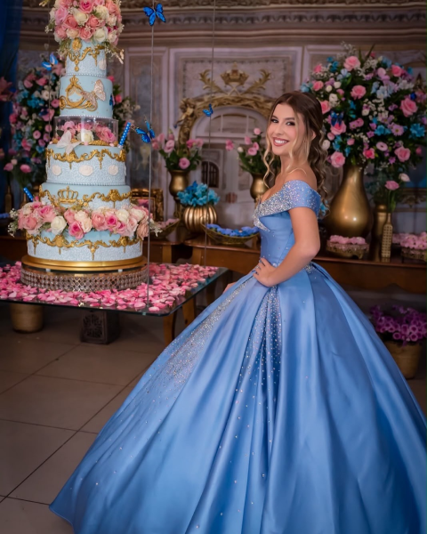 Debutante em vestido azul claro ao lado de bolo decorado