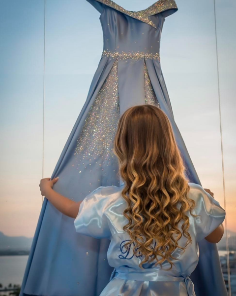 Debutante com vestido azul em vitrine ao pôr do sol